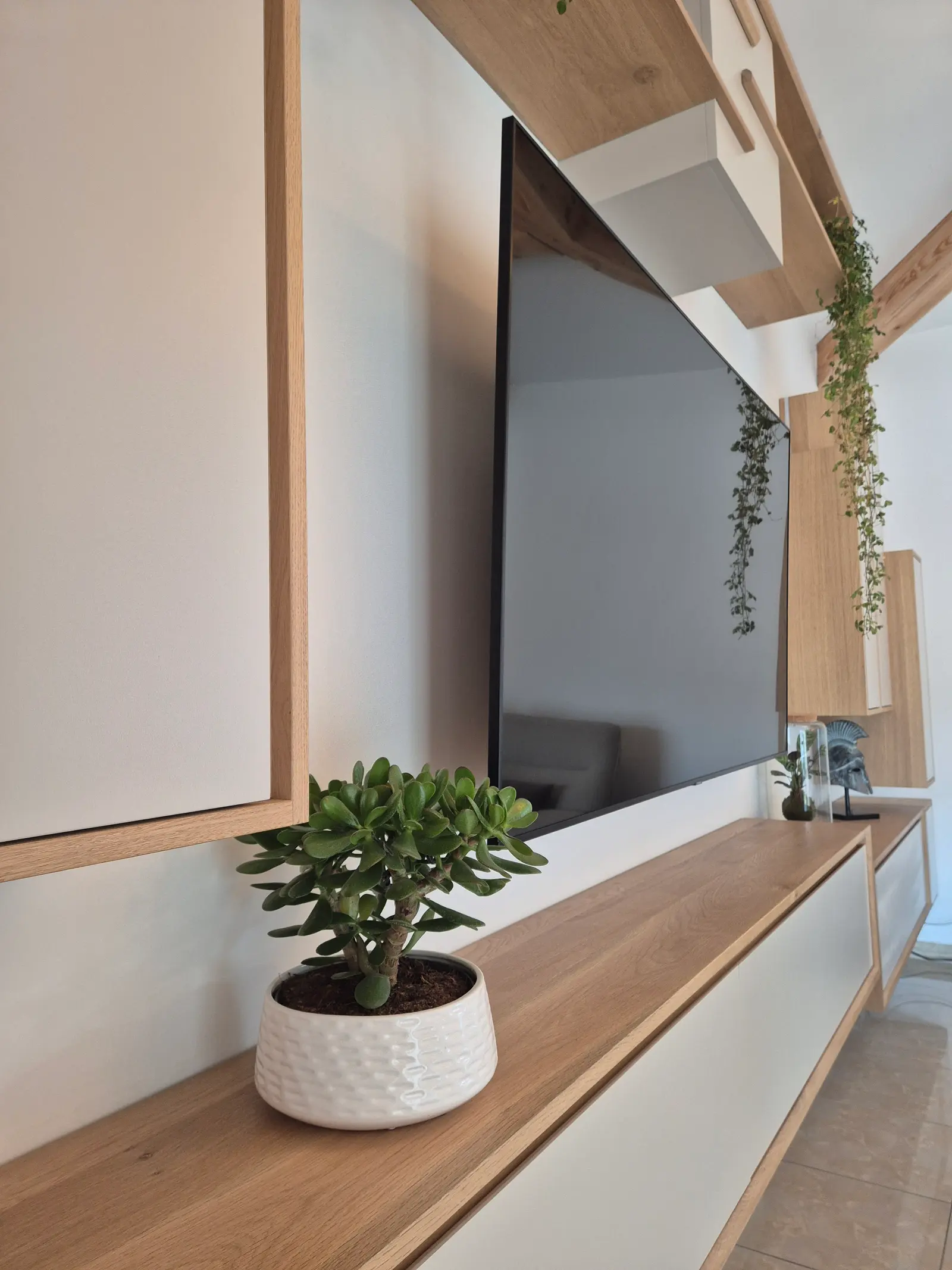 Détail d'un meuble TV suspendu sur mesure en chêne massif avec jardinières intégrées, menuiserie d'agencement à Marseille