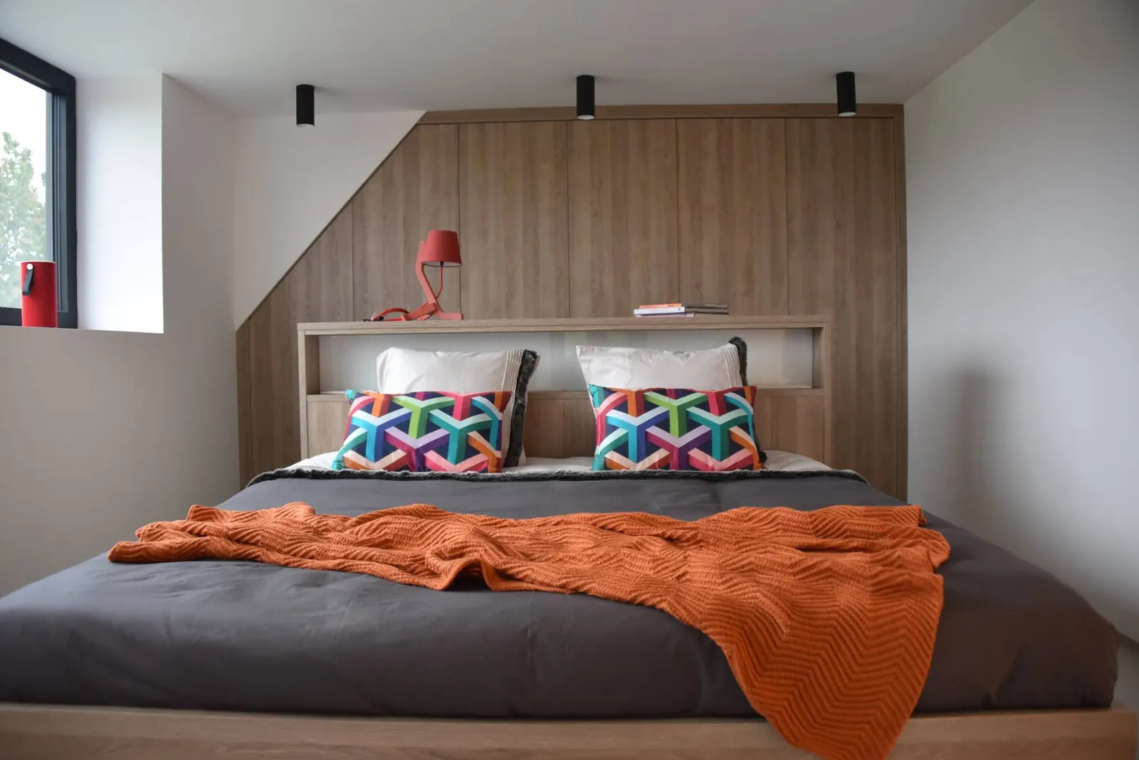 Chambre avec tête de lit et dressing sous pente sur mesure en bois clair, mobilier conçu par AD Design Archi à Marseille
